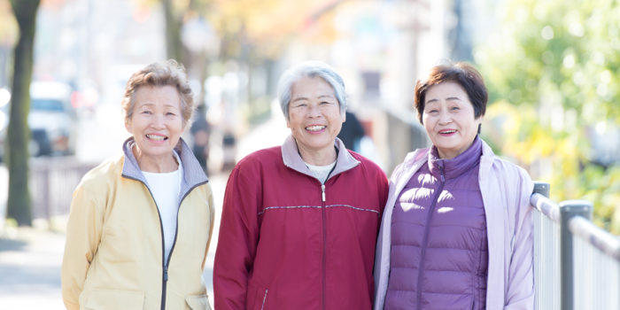 3 elderly asian women standing in the street together smiling
