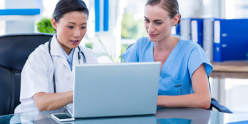 A doctor and a nurse reviewing patient wound care information on a laptop using PointClickCare's Skin and Wound solution