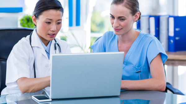 A doctor and a nurse reviewing patient wound care information on a laptop using PointClickCare's Skin and Wound solution