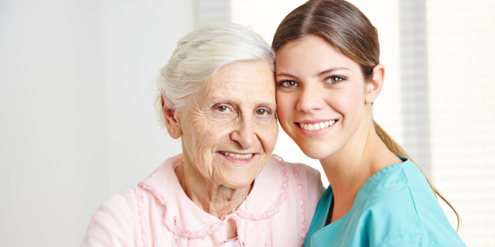 A senior care nurse standing with an elderly patient, keeping her engaged