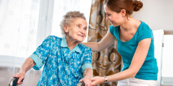 A nurse working with an elderly patient to regain her strength and prevent further injury