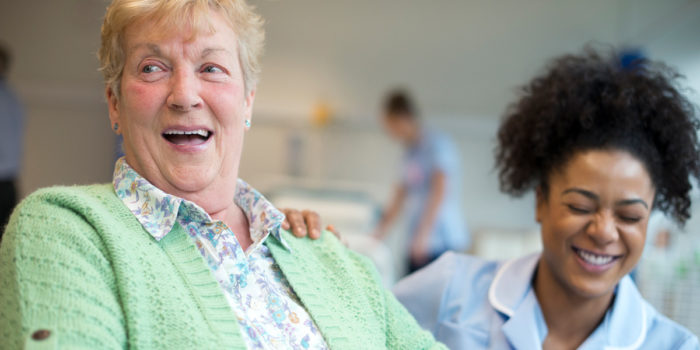 A nurse and an elderly patient laughing together