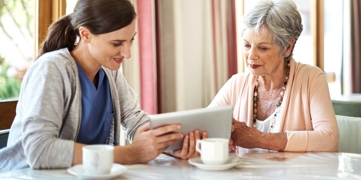 A senior care administrator sitting with an elderly patient reviewing their data to make informed decisions about her care
