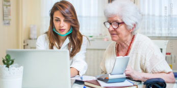 A home health care professional sitting with her elderly resident, documenting the Home Health Care services