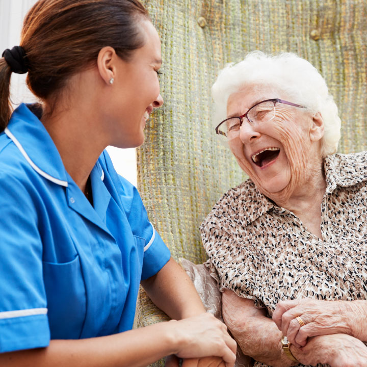 A Senior Living nurse laughing with an elderly resident.