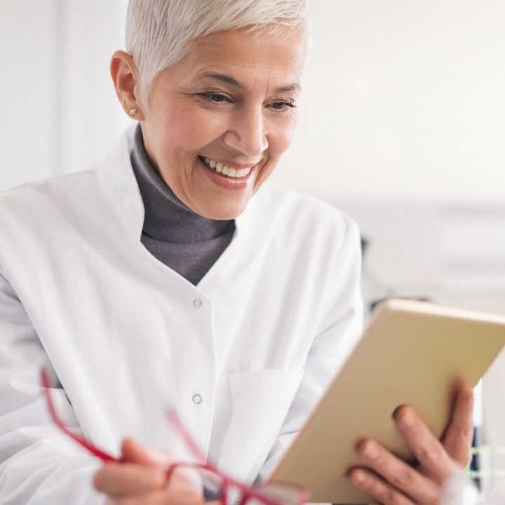 A female skilled nursing provider smiling and looking at integrated results on a tablet device