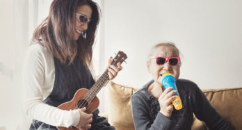 Resident singing on a microphone and a skilled nursing provider playing a ukulele to improve resident engagement