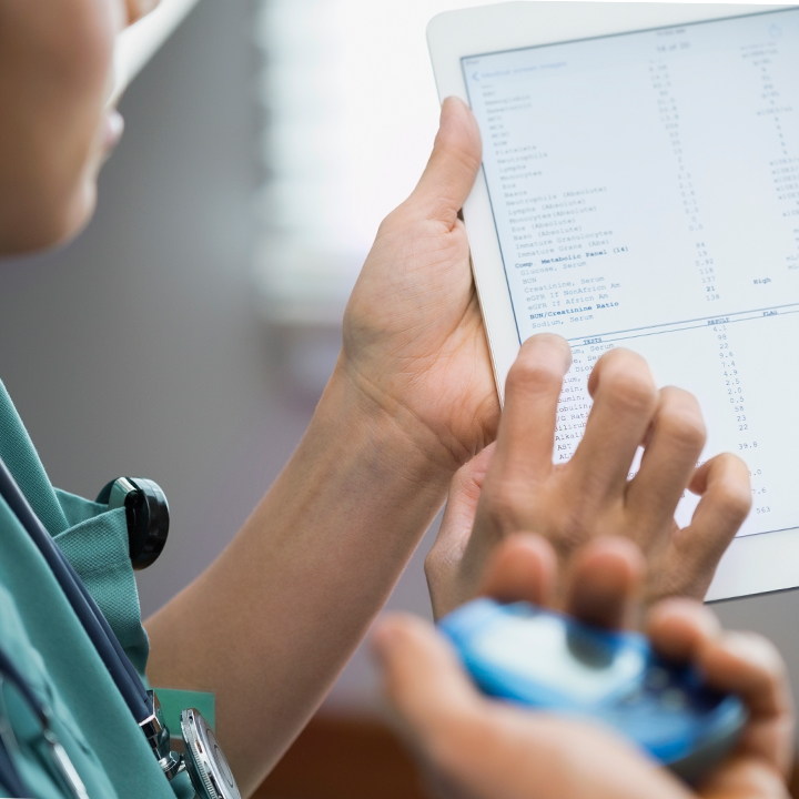Close up of a doctor's hands holding a tablet device that has patient information open