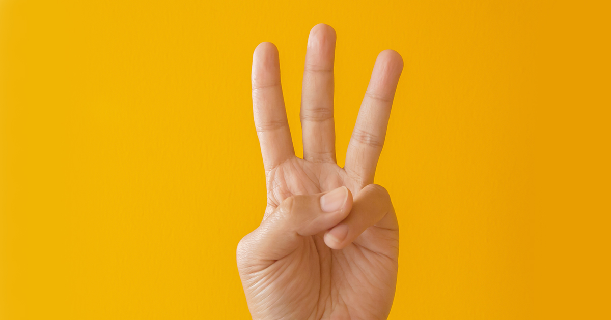 Hand with index, middle, and ring finger up with a yellow background