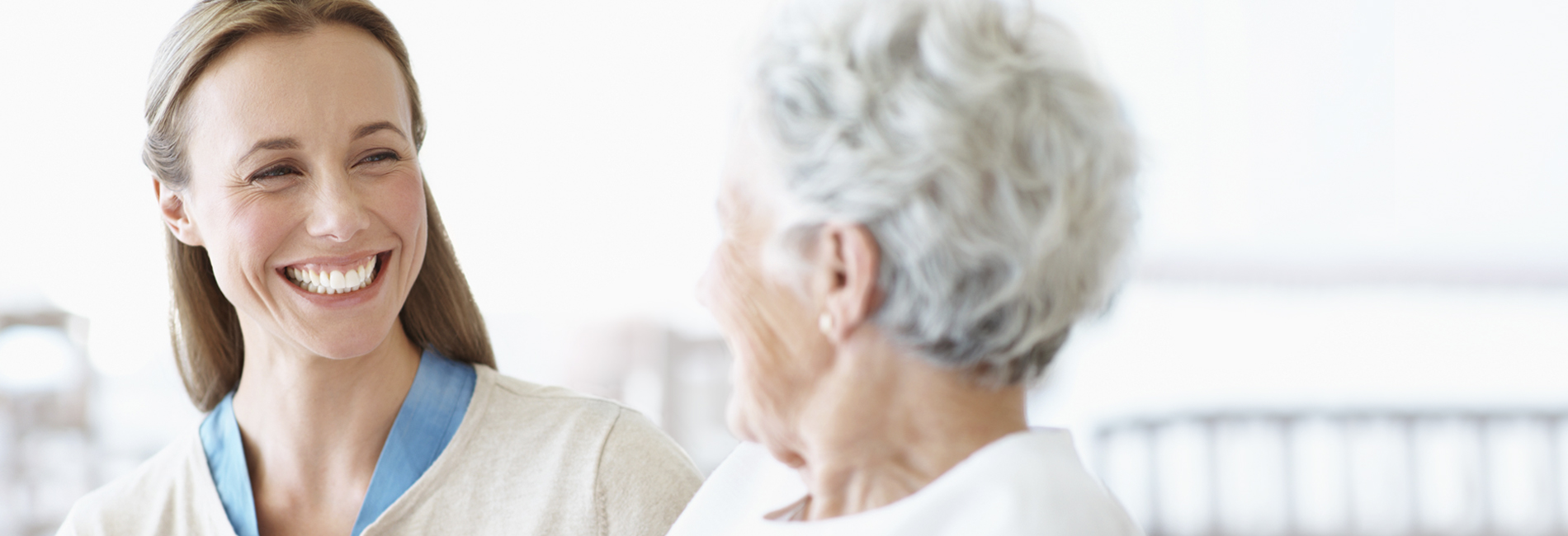 Female senior living provider with a big smile on her face while speaking to a female resident