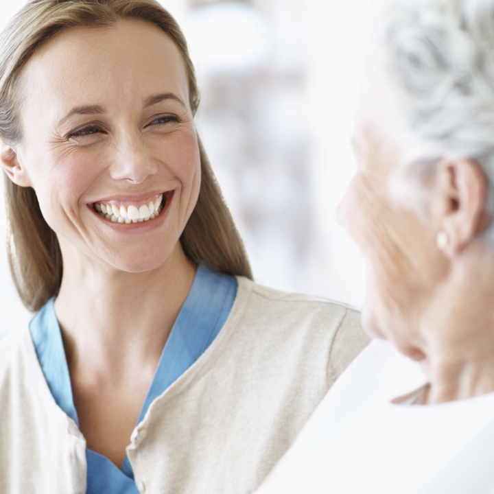 Female assisted living care provider smiling at a female resident