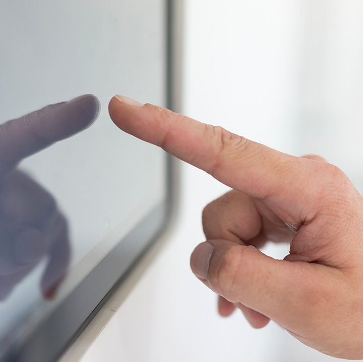 Close up of a hand with index finger about to touch a touchscreen device
