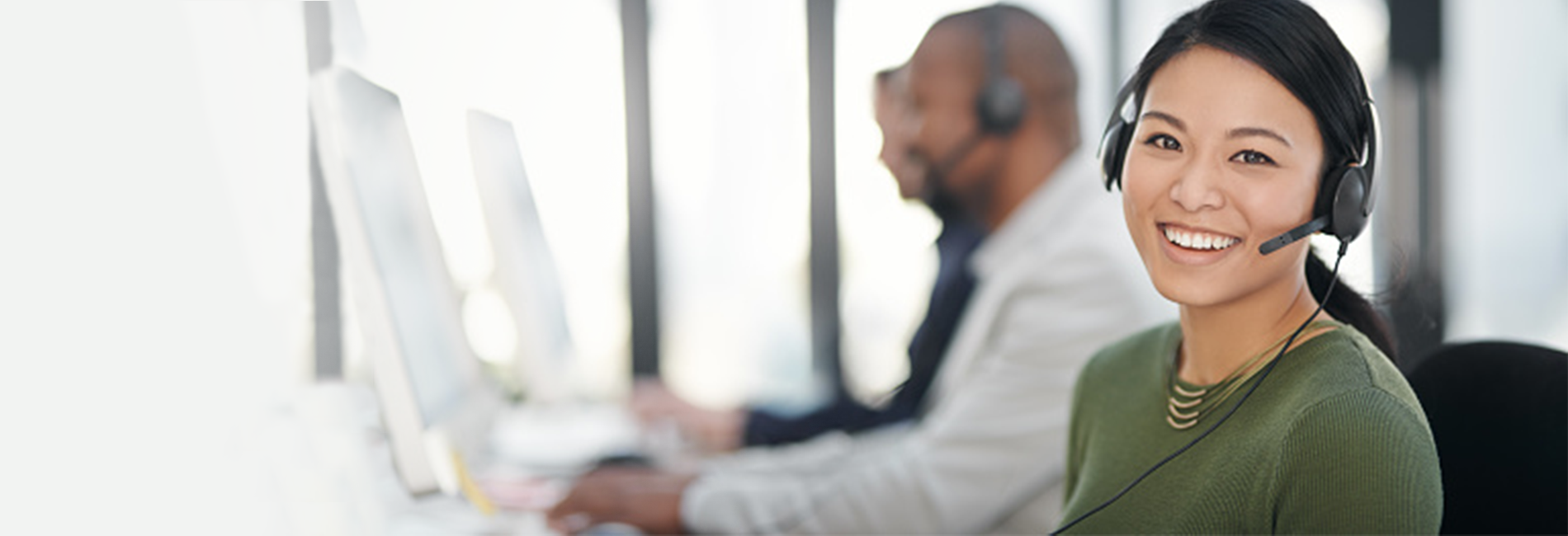 Office professionals wearing headsets speaking with customers while inputting data on desktop computers