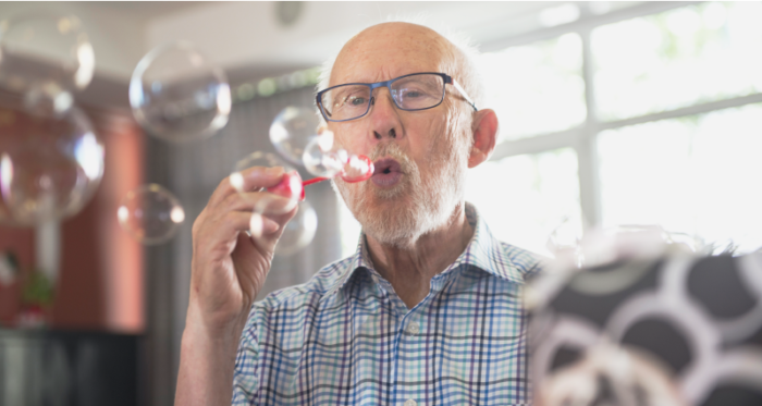 A male senior living resident blowing bubbles as part of a resident engagement program