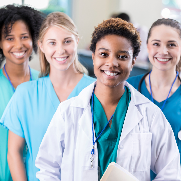 Team of four female skilled nursing providers wearing scrubs smiling