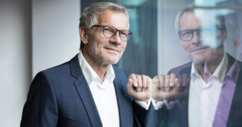 A male CFO smiles while looking out of a window