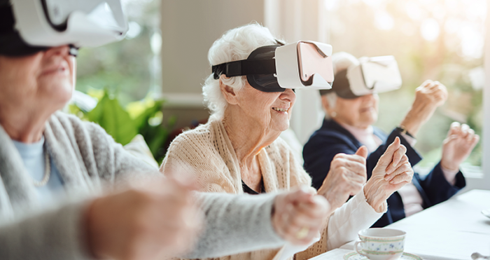 Three seniors smile while using virtual reality headsets