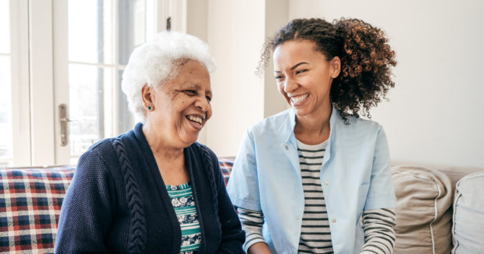 A caregiver laughs while spending time with an elderly patient.