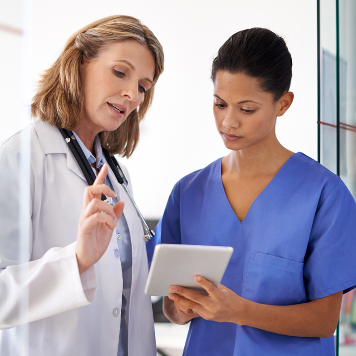 A doctor advising a nurse after reviewing a patient record using Carequality on a tablet