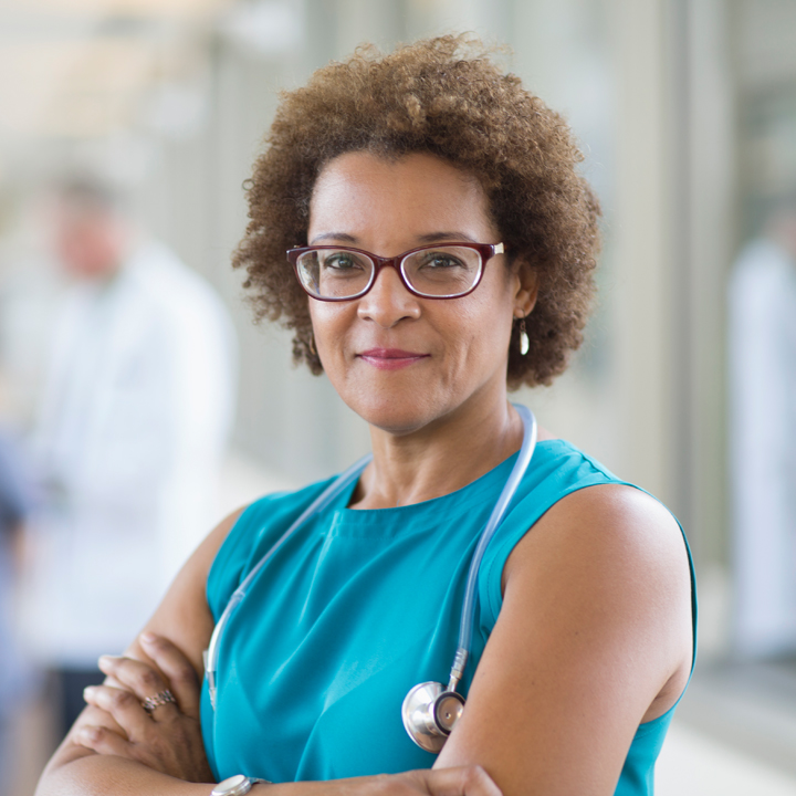 A doctor standing confidently as she thinks about empowering her care staff