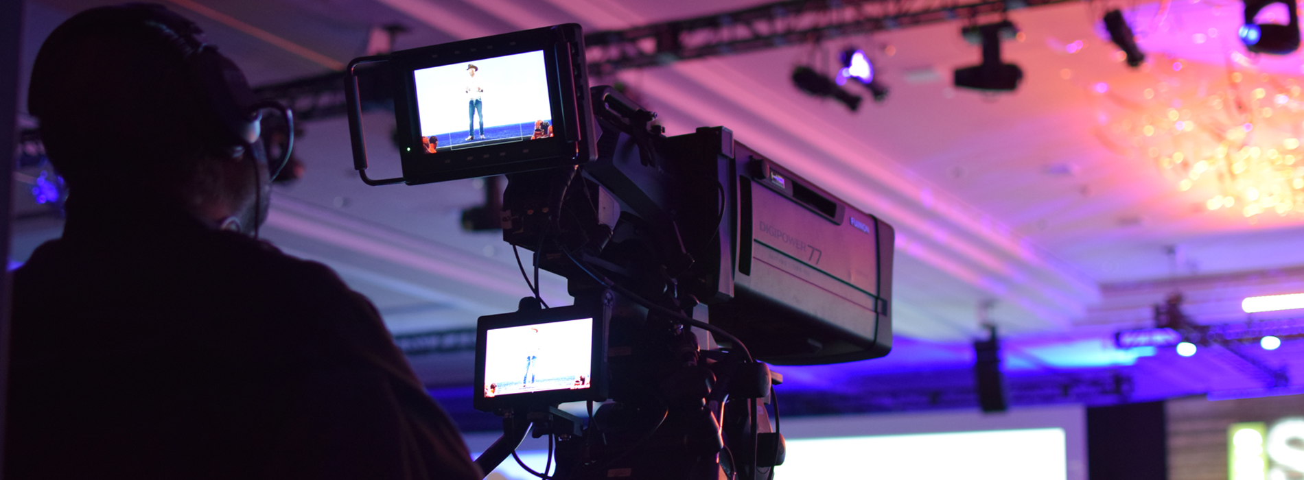 A cameraman operating a video camera and recording Dave Wessinger on Stage and SUMMIT 2019