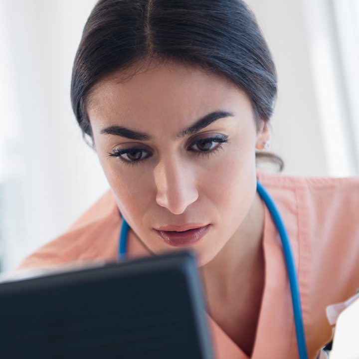 A nurse reviewing patient infection information on laptop