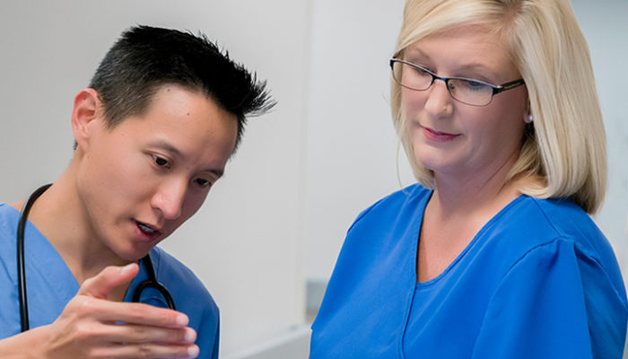 Healthcare workers reviewing patient infection information using PointClickCare's Infection Prevention and Control on laptop