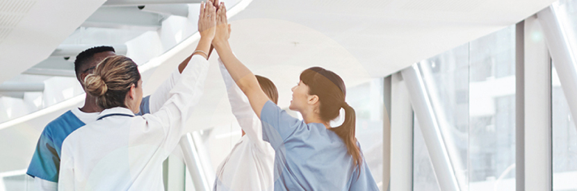 A group of medical staff high fiving in a corridor as PointClickCare is recognized in the 2020 Health Innovation Awards by Microsoft