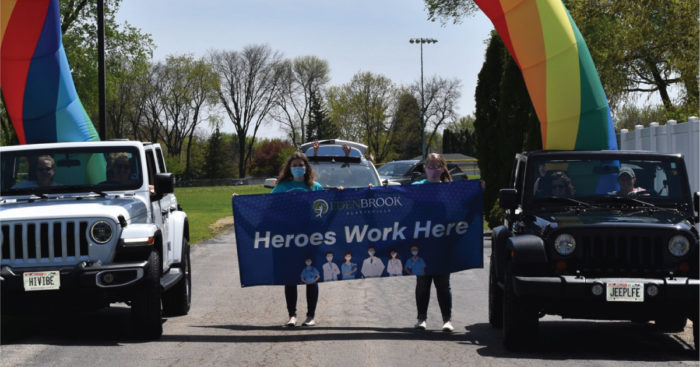 Two women hold a banner that reads "Heroes Work Here."
