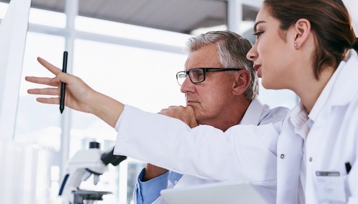 A doctor and scientist reviewing data on a monitor