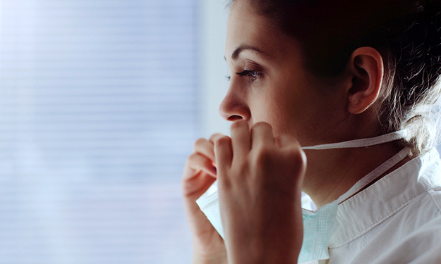 A nurse putting on a face mask