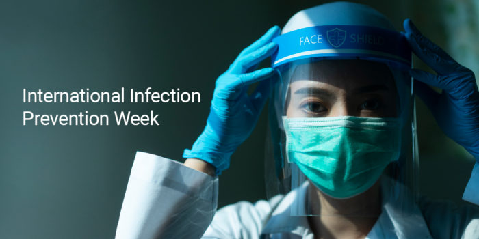 A medical professional wearing PPE and posing for a photo for International Infection Prevention Week
