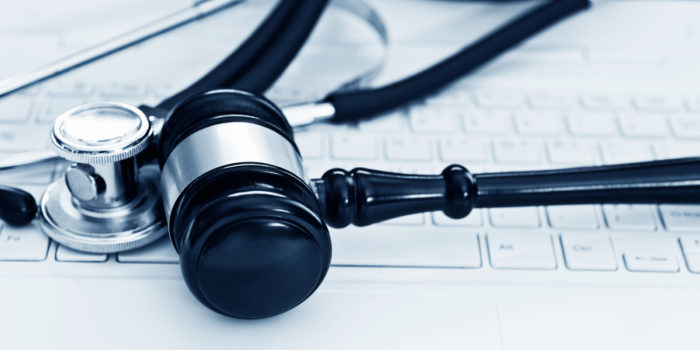 A gavel and stethoscope placed on top of a laptop's keyboard