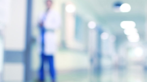Blurred effect over a hospital corridor with a male doctor standing close to a door