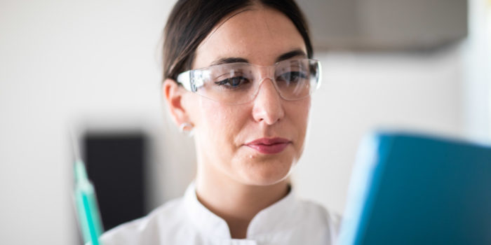 Close up of a female epidemiologists' head as she is wearing protective eye glasses and looking over information