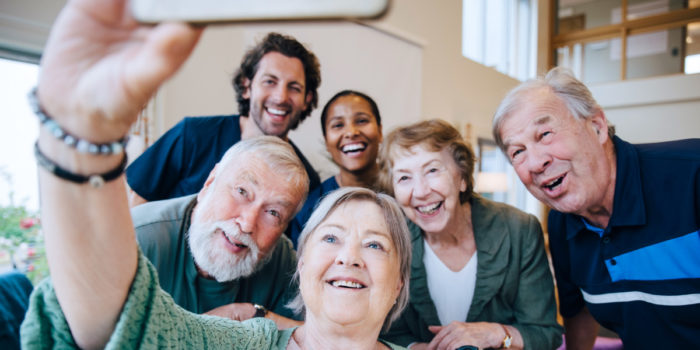 Senior living residents and staff laughing as they pose for a selfie