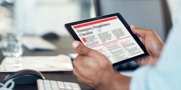 Close up of hands holding a tablet device that has an Emergency Preparedness Checklist open