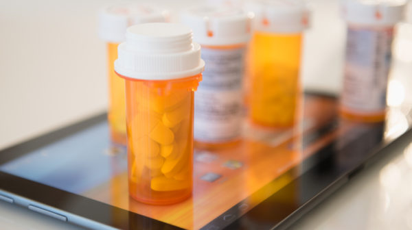 Several prescription medication bottles placed on top of a tablet device that is on a table