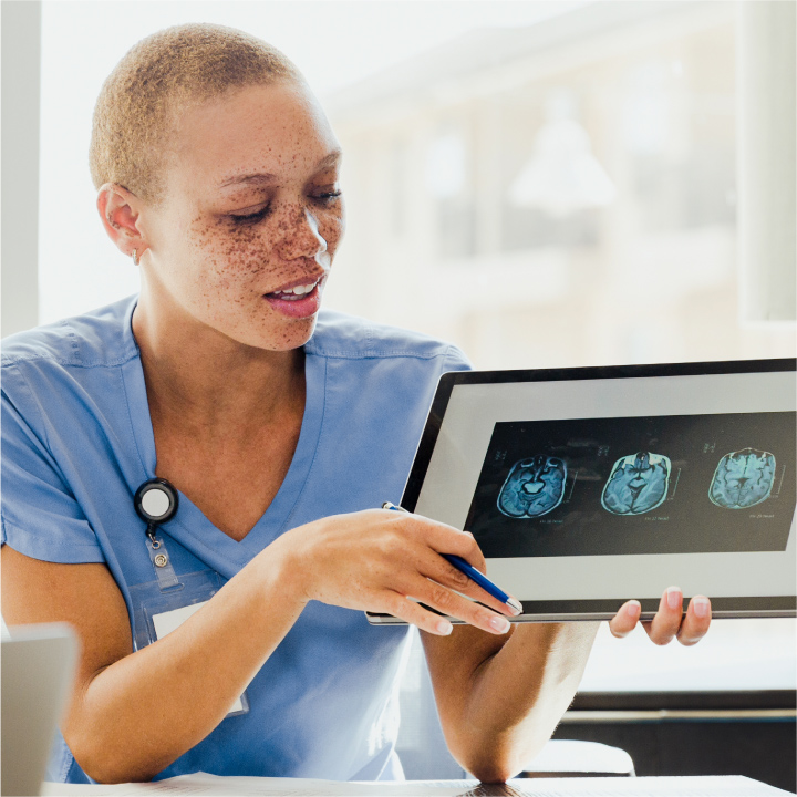 Female nurse seated and reviewing imaging results for a patient's scan on a digital device
