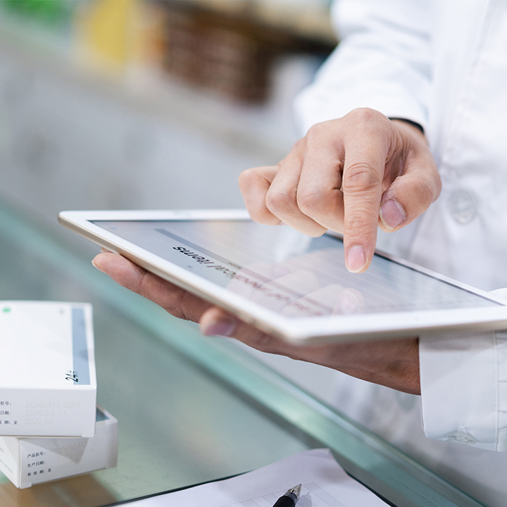 Close up of a skilled nursing providers hands holding a tablet device and reviewing medication management data