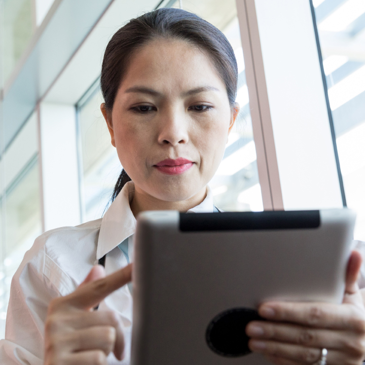Female senior living community staff member next to a window and looking down at a tablet device