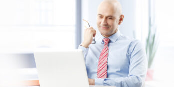 Male life sciences company executive sitting in his office and looking at his laptop