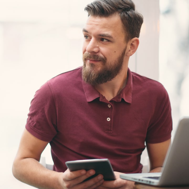 Male Infection Prevention expert seated and holding a tablet device with both his hands while he has a laptop open in front of him