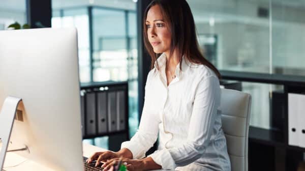 Female case manager sitting her in office focused doing work on a desktop computer