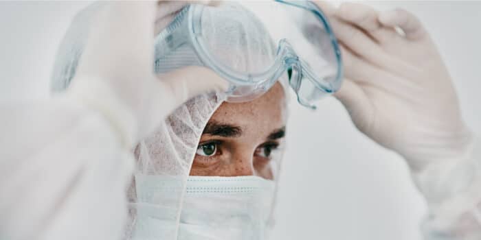 Close up of a healthcare worker's head while they are lowering their protective goggles over their eyes