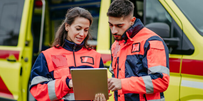A woman and man dressed in emergency response gear, examining and discussing information on a note pad.